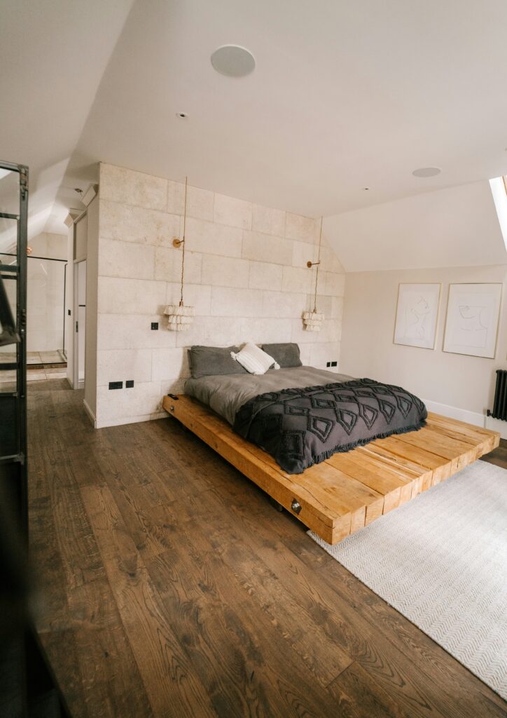 Low plywood platform bed in a cozy attic-style bedroom with wooden flooring